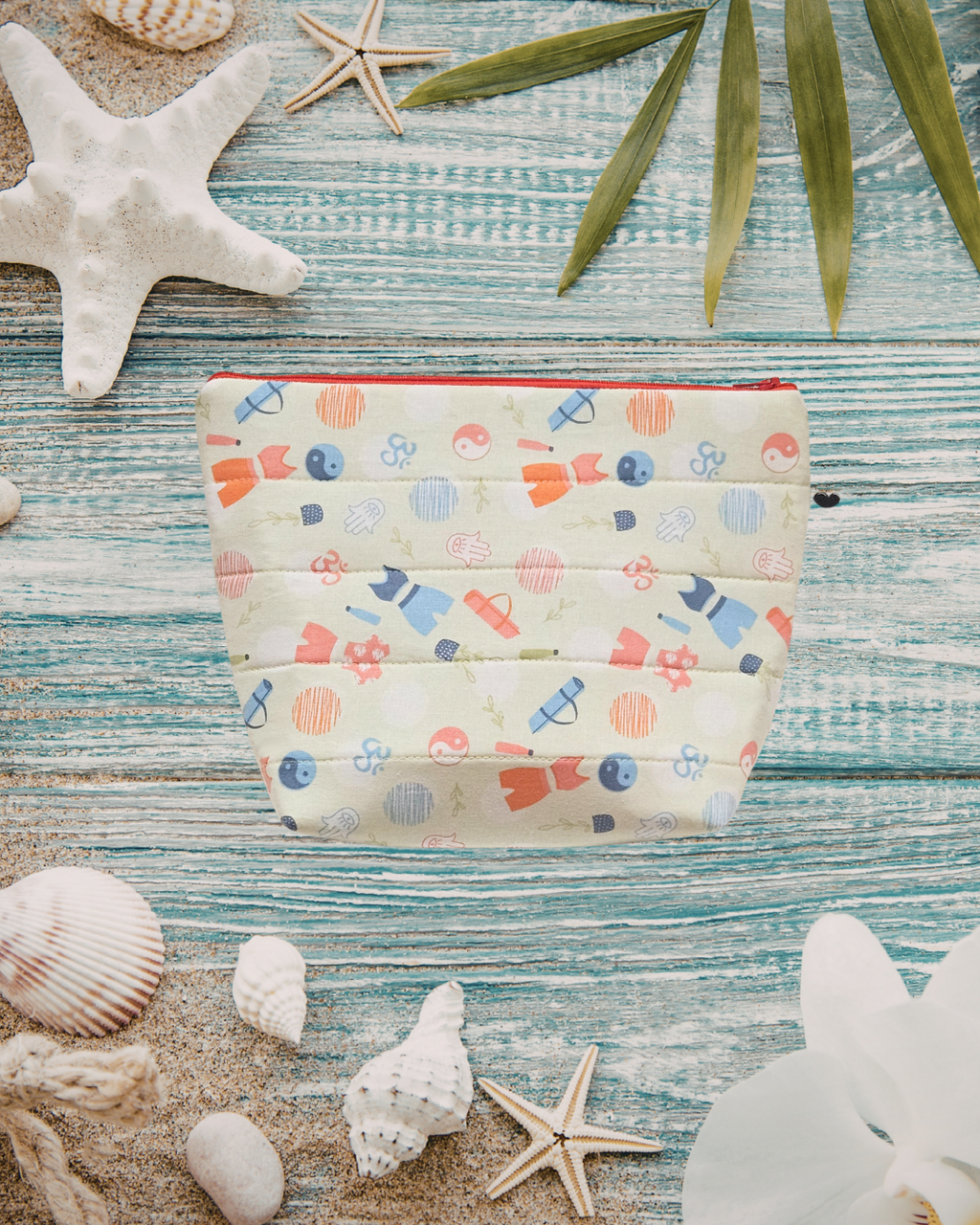 Featuring a calming sage green base with bold orange and red yoga-inspired accents, this pouch blends playful colour with practical design.