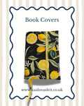 A book cover featuring a black background with a lemon and leaf floral print, secured with a yellow zipper and green button, shown on a white background with decorative blue border and text reading 'Book Covers' and 'www.kaalimadeit.