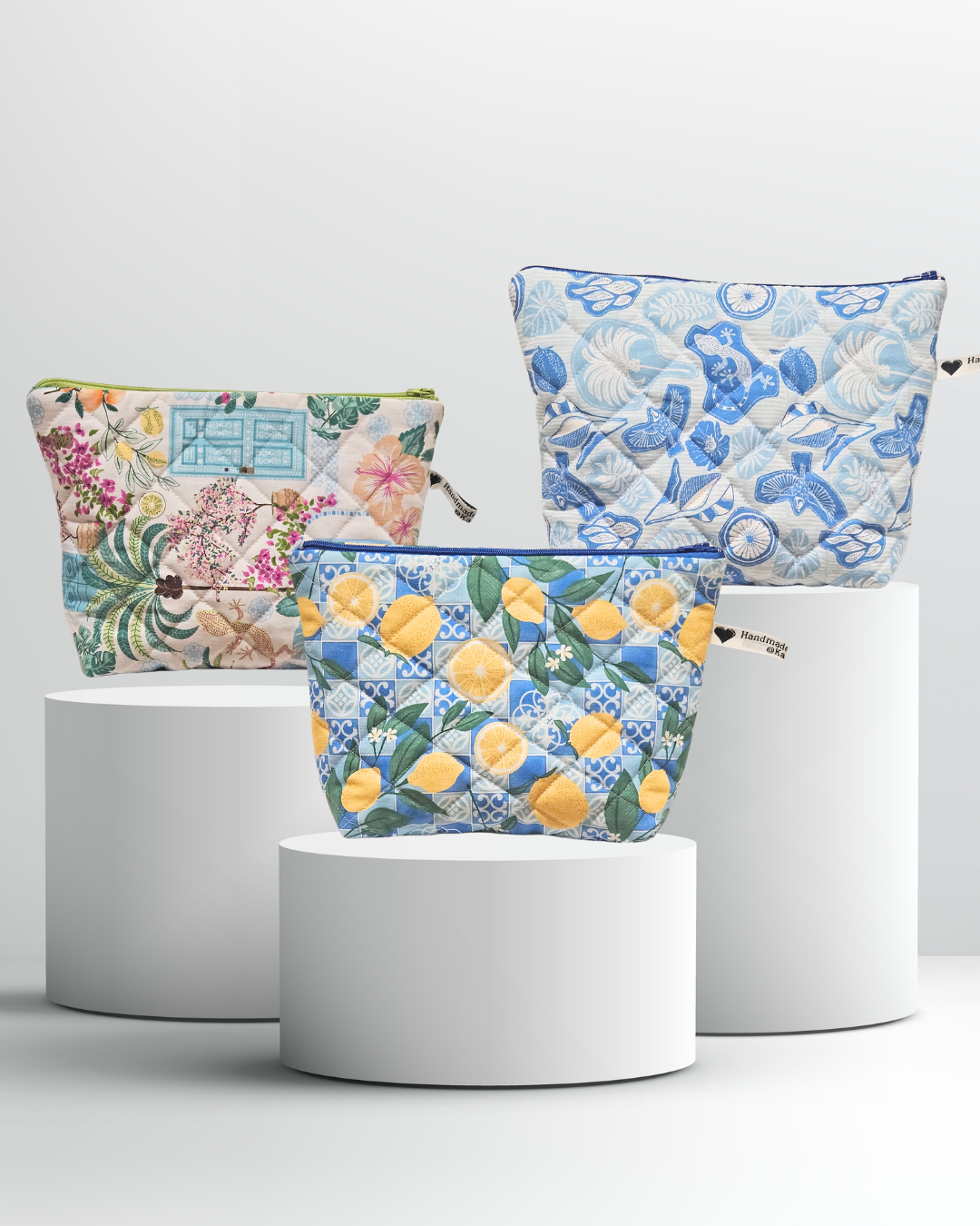 Three floral-patterned pouches on white cylindrical stands against a light gray background