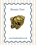 A beauty tote bag with a black and gold baroque pattern, presented on a white card with a wavy blue border. The card features the text 'Beauty Tote' and the website 'www.