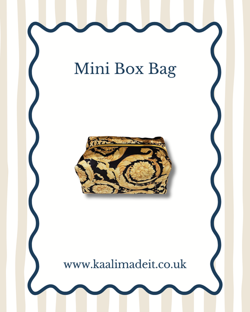 A mini box bag with a black and gold baroque scroll pattern, presented on a white card with a wavy blue border. The card features the text 'Mini Box Bag' at the top and 'www.